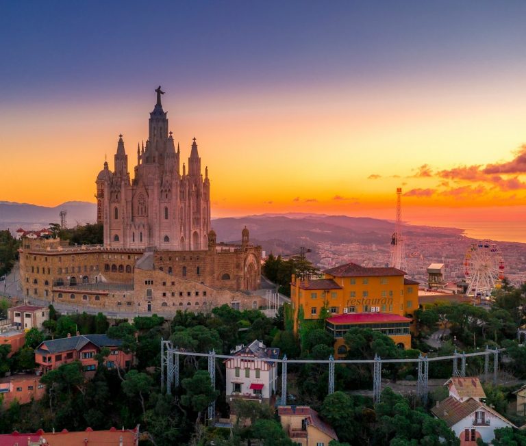 Vue du château de Montjuïc au coucher du soleil, avec des bâtiments colorés en foreground.