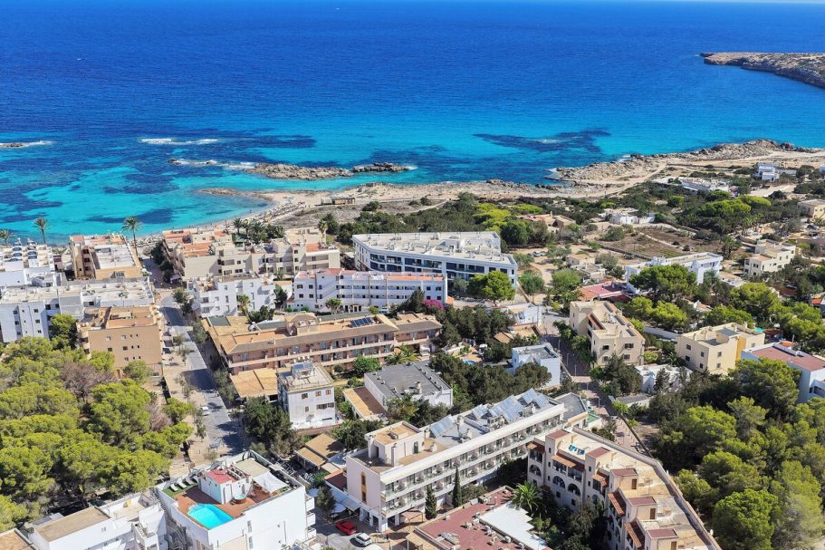 Vue aérienne d'un littoral, avec des bâtiments, des plages et une mer turquoise.