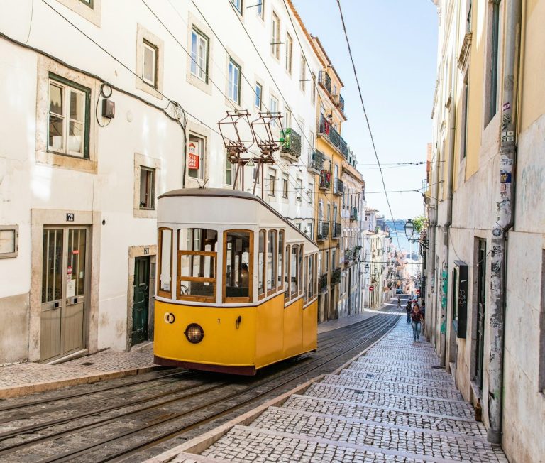 Un tramway jaune monte une rue pavée étroite à Lisbonne.